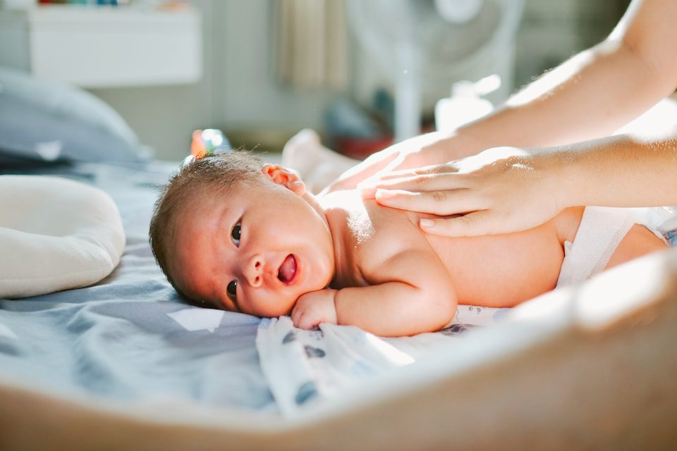 Hand einer Mutter streicht sanft über den Kopf ihres Babys