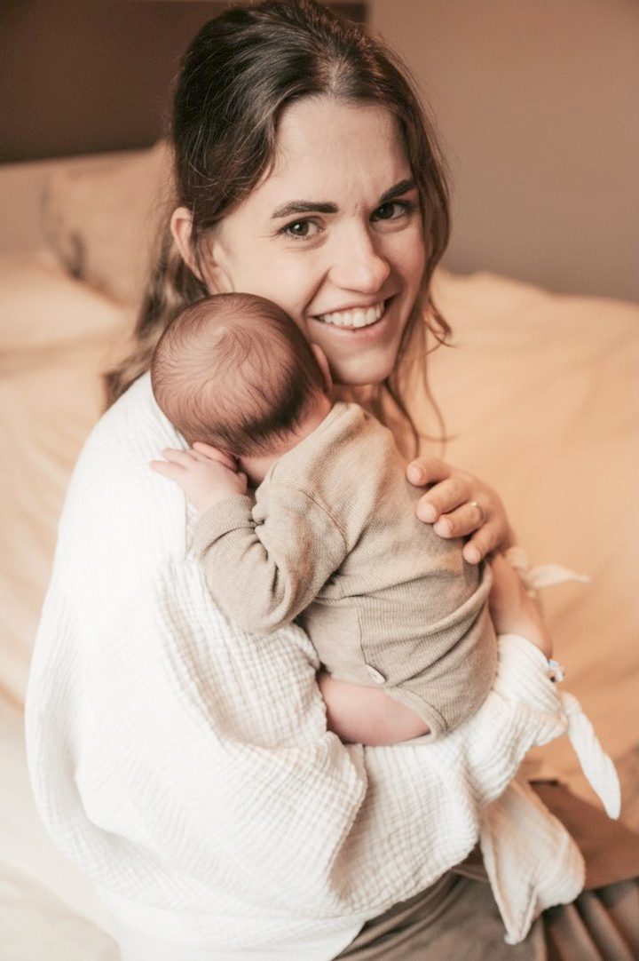 Conny hält lächelnd ihr Baby im Arm